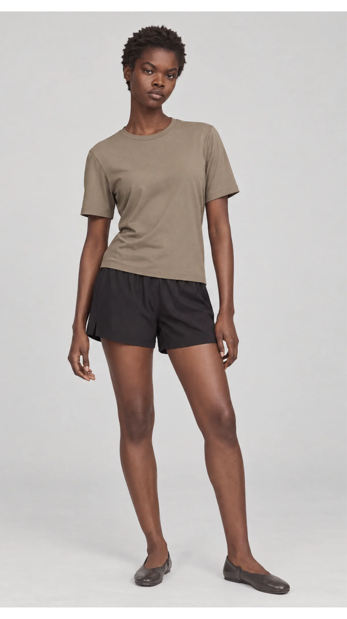 Front catalogue view of a model wearing a taupe T-shirt and black shorts