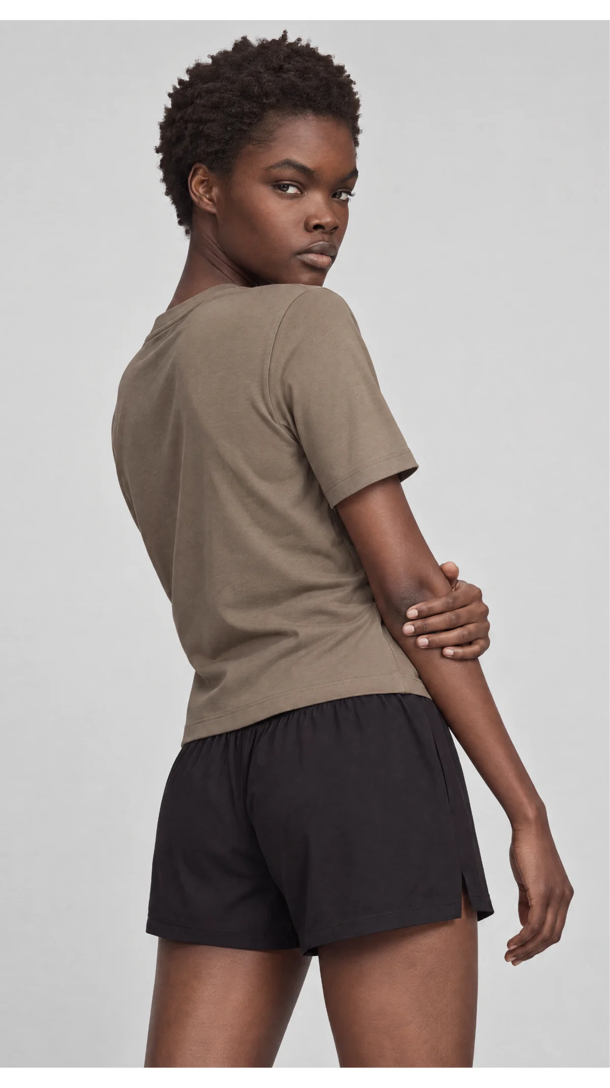 Three-quarter catalogue view of a model wearing a taupe T-shirt and black shorts
